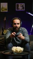 Vertical Cheerful gamer celebrating, showing positive emotions after defeating all enemies while playing on gaming console. Man congratulating himself after winning videogame, feeling relieved, camera B video