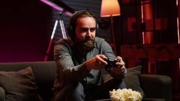 Cheerful gamer celebrating, showing positive emotions after defeating all enemies while playing on gaming console. Man congratulating himself after winning videogame, feeling relieved, camera A video