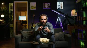 Cheerful gamer celebrating, showing positive emotions after defeating all enemies while playing on gaming console. Man congratulating himself after winning videogame, feeling relieved, camera B video