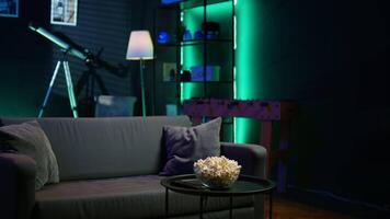 Contemporary living space with remote control and snacks on table reflecting preparation for movie night, panning shot. Close up of popcorn bowl in apartment with relaxing atmosphere video