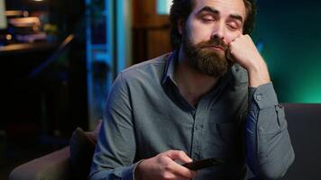 uomo annoiato a casa ricerca per tv serie per abbuffata su streaming Servizi, procrastinare. vicino su di persona seduta su divano, capovolgimento anche se tv canali utilizzando a distanza controllo, telecamera un' video