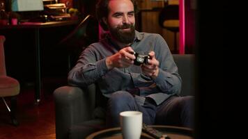 Man enjoying playing videogame in neon lit room, holding controller. Gamer participating in internet esports competition using professional gamepad for better victory chances, camera A video