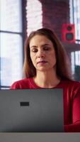 vertical confiante mulher resolução dela tarefas em uma freelance plataforma às lar, respondendo e-mails e multitarefa. maduro trabalhador ficando conectado e desfrutando a flexibilidade do trabalhando remotamente. Câmera uma. video