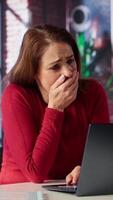 Vertical Exhausted woman trying to solve daily tasks on laptop at home office, struggling to pay attention to remote freelance work. Person yawning and being overworked surfing the web. Camera A. video