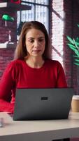 Vertical Mature girl freelancer managing her creative projects remotely in loft, working on a new novel or script for her gig. Woman focusing on writing and editing her creation, telework. Camera B. video