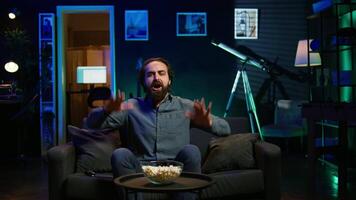 Fan watching live sports event on TV, chanting for team, having fun, doing choreography dance. Supporter at home doing energetic hand gesturing, cheering for own club to win, camera B video