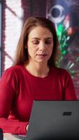 vertical focado mulher acionado dentro conectados pesquisa para uma trabalhos projeto às casa escritório, sentado às a computador portátil e lendo artigos em rede. pessoa surfar paginas web e encontro dados, teletrabalho. Câmera uma. video