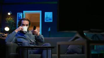 Man appalled by upsetting breaking news story on TV, doing phone call to family member. Person at home scared by troubling events broadcasted on TV, calling friend using smartphone, camera B video