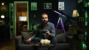 Smiling man putting headphones on to play videogames on gaming console with teammates. Happy player enjoying defeating foes in game, discussing with friends through headset, camera B video