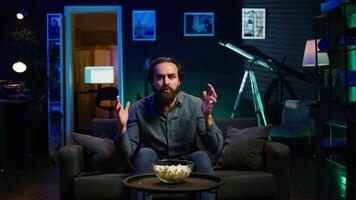 Frustrated supporter watching sports match on live broadcast, upset by team mistake. Man at home on couch looking at football competition, dejected by chance missed by player, camera B video