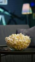 Vertical Snack prepared for movie night in dimly illuminated modern apartment home theatre. Empty neon lit cozy residential interior with sofa and bowl of popcorn on coffee table. video