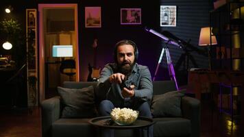 Gamer feeling overjoyed after winning videogame level, screaming in excitement. Ecstatic man at home yelling from joy after achieving victory while playing on gaming console, camera B video