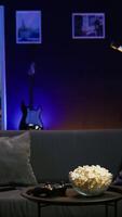 vertical jugador en sofá en Departamento atractivo en en línea competitivo multijugador torneo utilizando mando hombre en hogar teatro jugando atractivo videojuego con controlador, comiendo Palomitas, cámara si video