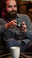 Vertical Man enjoying playing videogame in neon lit room, holding controller. Gamer participating in internet esports competition using professional gamepad for better victory chances, camera A video