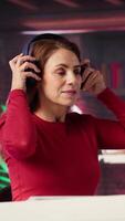 Vertical Female freelancer using ambience music on headphones to solve her tasks efficiently, working at home and multitasking with audio experience. Mature woman enjoying remote job. Camera A. video