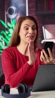 Vertical Mature adult smiling and waving during a call at home desk, showcasing modern technology and online communication in a digital and wireless lifestyle. Web conference on phone. Camera A. video