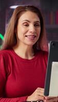 Vertical Focused woman smiling and waving during a web conference at her home, showcasing virtual meeting and online communication in a digital and wireless lifestyle. Ecstatic conference speaker. Camera A. video