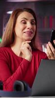 Vertical Woman freelancer taking online course to develop new skills from home office, attend online call and watching lecture on smartphone. Lady participates at virtual training class. Camera A. video