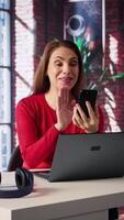 Vertical Mature adult smiling and waving during a call at home desk, showcasing modern technology and online communication in a digital and wireless lifestyle. Web conference on phone. Camera B. video