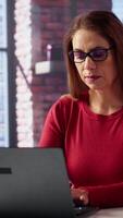 Vertical Mature person overseeing business schedule and planning activities at desk, working on time management with digital tools. Female freelancer utilizing the pc and multitasking. Camera A. video