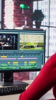 Vertical Female filmmaker working on media post production from agency office, ensuring the editing timeline and color correction for shoot. Tech driven workspace showcases workflow. Camera B. video