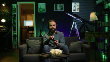 Satisfied gamer bragging after finally defeating all enemies while playing on gaming console. Pleased player congratulating himself after winning videogame using controller, camera B video