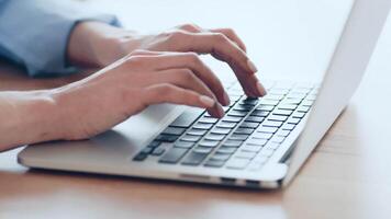 A person is actively typing on a laptop, positioned on a sleek wooden desk. Natural light floods the area, enhancing focus and creating a productive atmosphere for work. video