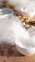 Serving the table with food and drinks with vessels with dry ice. Smoke on the table among an expensive yacht video