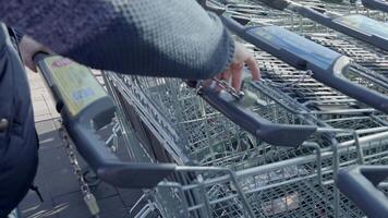 Bad Hersfeld, Germany, 03.02.25 The cart-locking system requires inserting a chain and taking a chip, preventing cart theft. This method ensures proper return and organization of shopping carts video