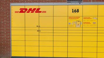 Bad Hersfeld, Germany, 03.02.25. A bright yellow DHL self-service post station with secure lockers, accessible by code. A small solar panel on the roof powers the system, ensuring eco-friendly package video