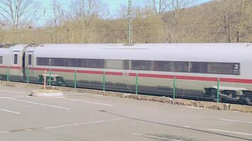 Bad Hersfeld, Germany, 03.02.2025 A high speed, gray colored German train zooms past a row of bushes and trees, moving swiftly along the tracks. video