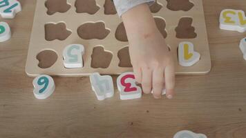the boy learns to count, holds a board with numbers-puzzles arranged in order from 1 to 20, the boy is 4-5 years old European appearance, at home sits at the table, preparation for school video