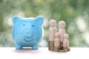 Model family with piggy bank and stack of coins money on natural green background photo