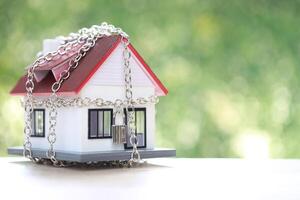 Debt,Locked house with padlock and chain on natural green background,Security and borrow mortgage failure crisis concept. photo