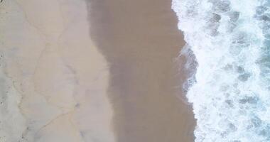 Directly above footage shot of ocean waves breaking on a beach shore, aerial drone view video
