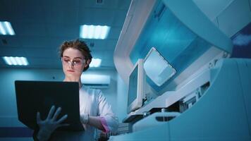 A young female robotics engineer with a laptop analyzing the concept of a robotic machine in a state-of-the-art lab. The concept of programming and data tracking to optimize robot performance video