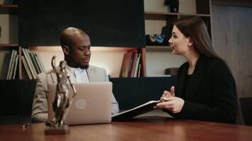 Focused African American businessman lawyer working with female client, using laptop computer, reading financial document report in office. Justice and law concept. video