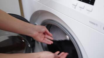 Woman loads dirty laundry into the washing machine and sets the wash cycle. Caring for cleanliness and comfort at home, simplifying daily life with modern technology video