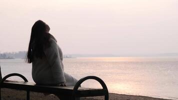 Woman relaxing on bench by lake enjoying sunset view video