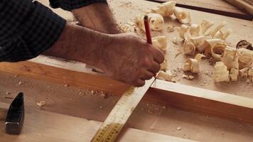 Craftsman measures and marks wooden board while working on carpentry project in workshop video