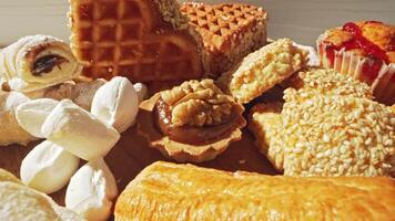 Assorted traditional pastries and sweets displayed on a wooden surface in bright sunlight during a festive gathering video