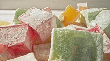 Colorful Turkish delight pieces are displayed in natural light on a wooden surface video