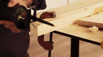 Someone is using a power saw to cut wood while it is securely clamped video
