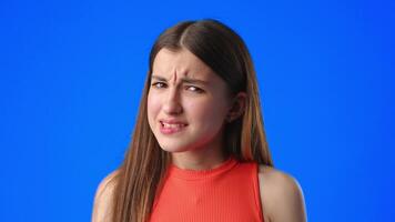 Girl with a confused expression on a bright blue background during a discussion or interview video
