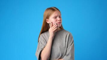 Thoughtful girl pondering questions against a bright blue background in a creative studio setup video