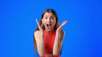 Excited girl shows her enthusiasm with a joyful expression and open hands against a bright blue background video
