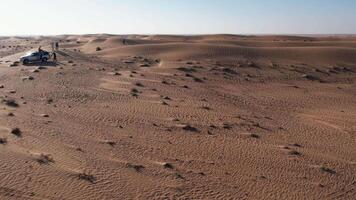 A drone over a lone man walking on a sand dune in the desert. Dubai, a sunny summer day video