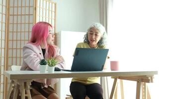 Digital Literacy and Intergenerational Learning. A daughter patiently teaches her elderly mother how to use a laptop, bridging the technology gap at home. video
