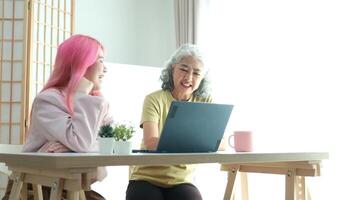 Digital Literacy and Intergenerational Learning. A daughter patiently teaches her elderly mother how to use a laptop, bridging the technology gap at home. video