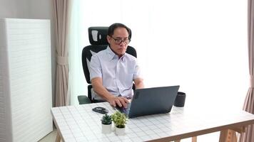 Elderly father using laptop to update news while relaxing in retirement at home. video